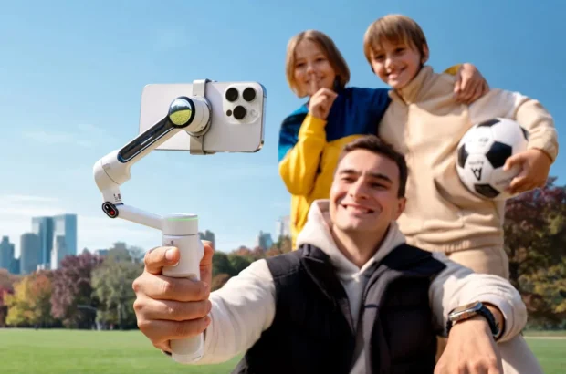 Мужчина удерживает белый стабилизатор Insta360 Flow Pro со смартфоном на магнитном зажиме и светящимся индикатором трекинга во время активной динамичной съемки в парке